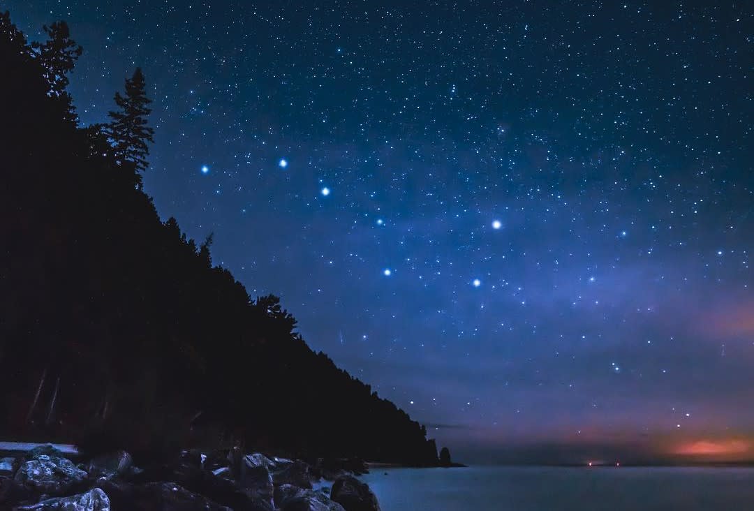 The Big Dipper Ursa Major constellation shines in the night sky above the water off Mackinac Island