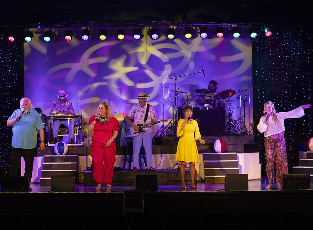 Three women and one man sing on stage during the Rudy Theatre's Throwback Sounds of Summer Program.