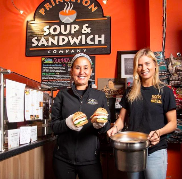 Smiling employees holding sandwiches in Princeton Soup and Sandwich