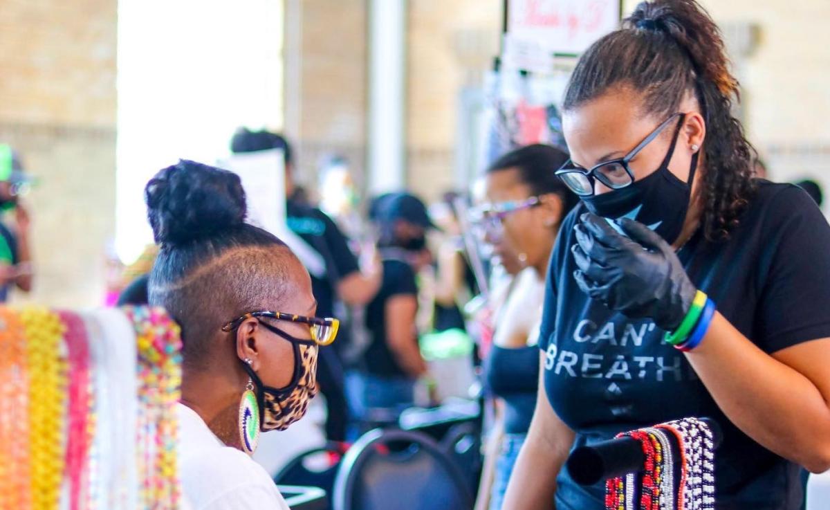 Two African-American women wearing face masks appear to be participating in a pop-up market.