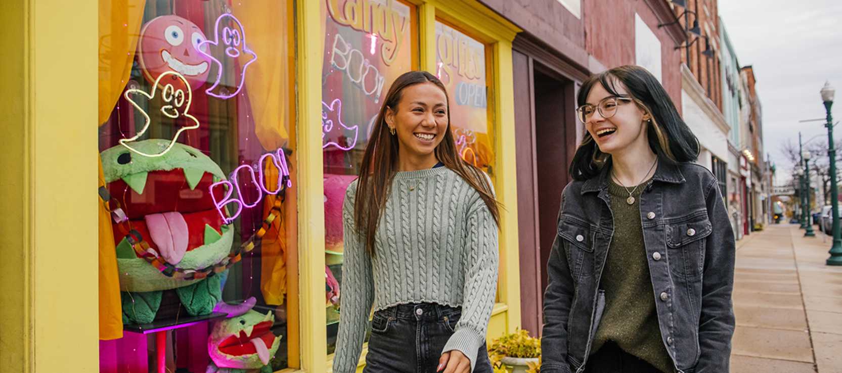 Two smiling woman walking down sidewalk