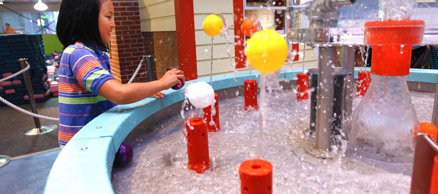 A little girl plays in an interactive water exhibit at the Hands-On Museum in Ann Arbor.