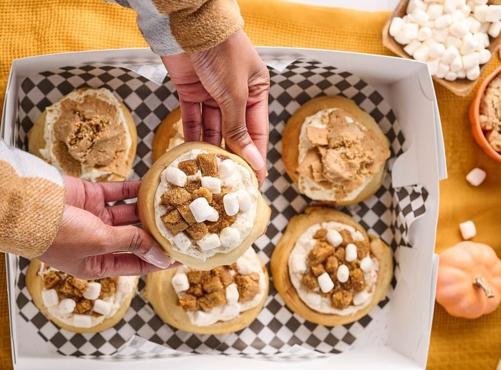 person grabs sweet treat from cinnaholic box