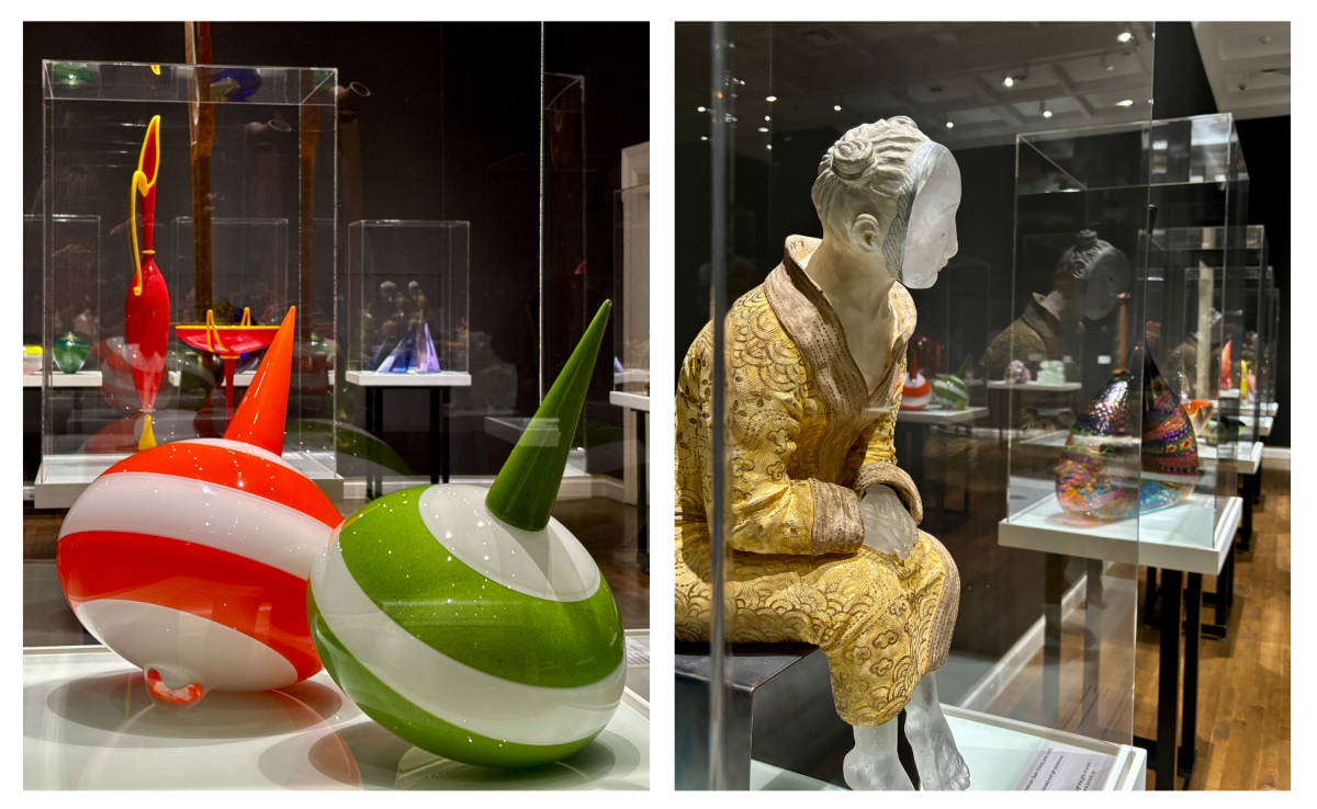 Exhibit at Muskegon museum of art featuring colorful, abstract glass sculptures on the left, and a detailed glass figure seated, facing a display case on the right.