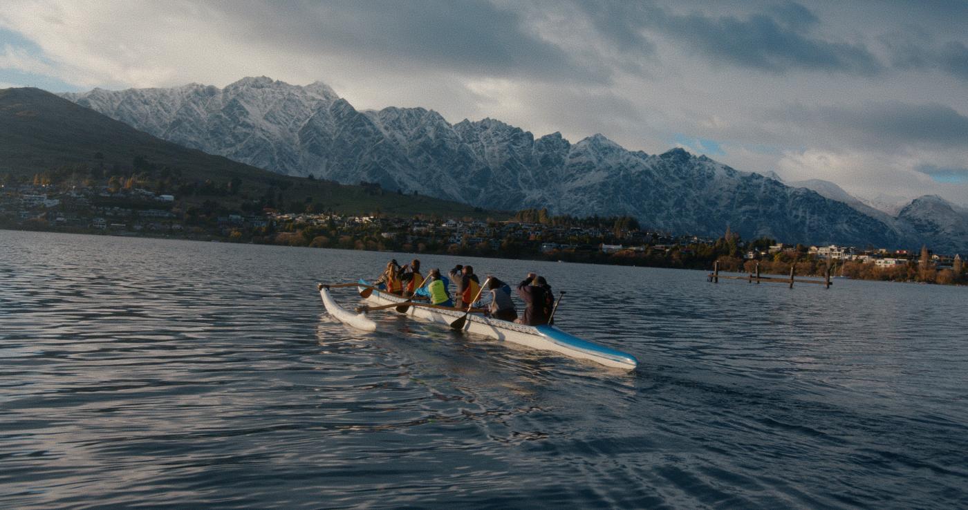 Waka Ama canoe paddling in front of mountains
