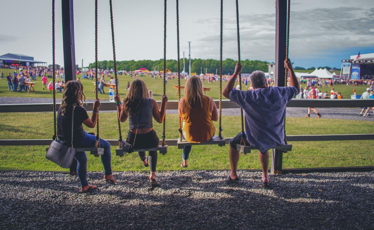 People sitting on wooden swings at Country Fest