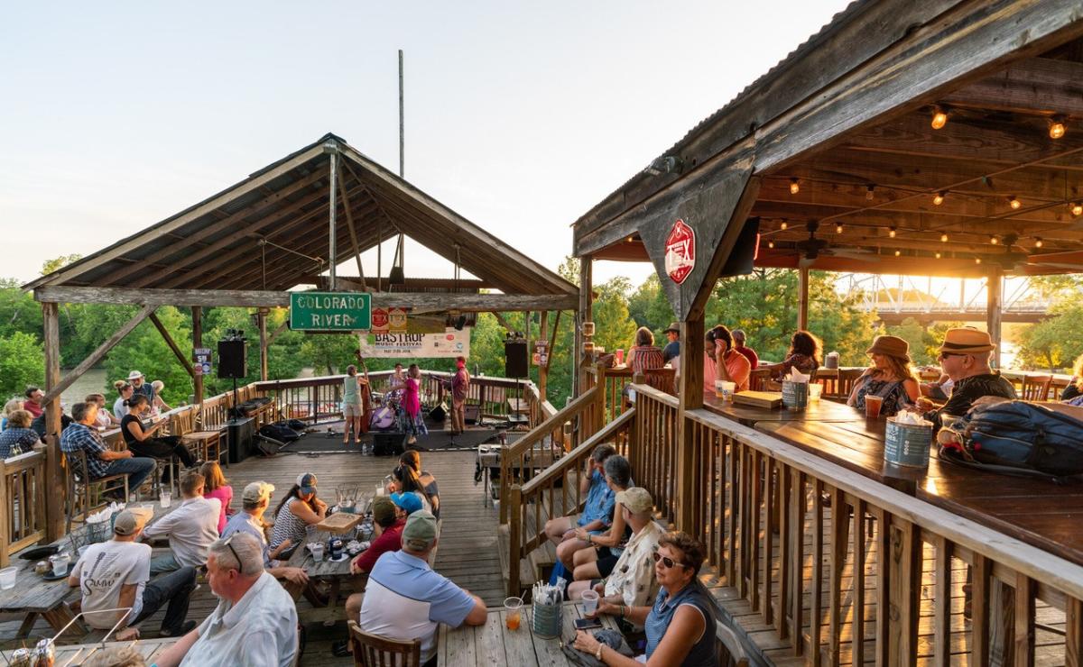 Image of people sitting on the patio at Neighbor's Kitchen & Yard with the sun setting in the background.