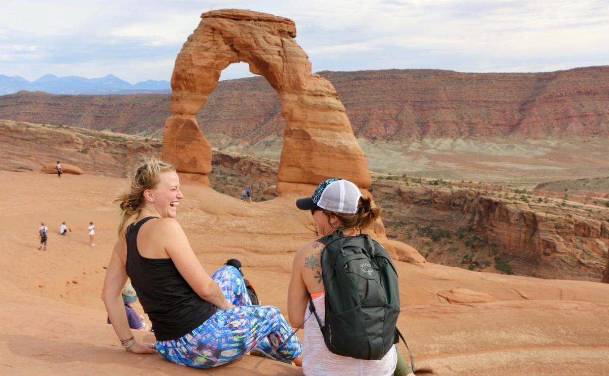 Two girls laughing at Delicate Arch at Arches National Park