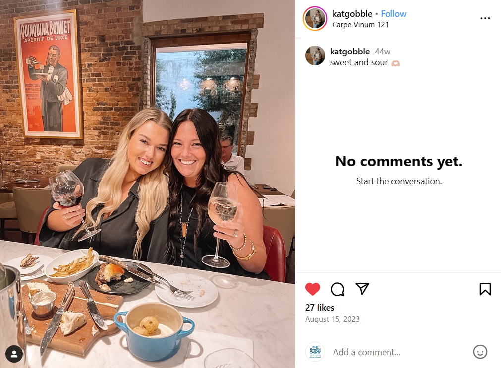 Two women at a restaurant holding up wine glasses
