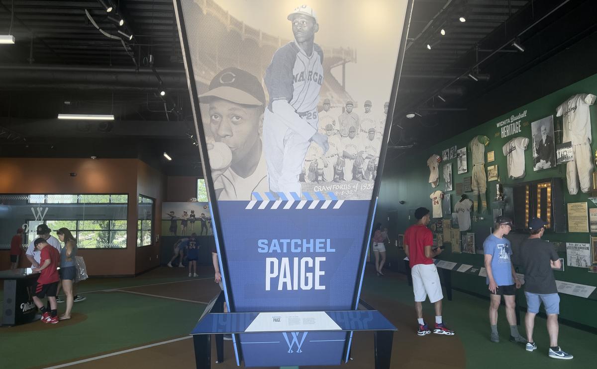 The Satchel Paige exhibit at the Wichita Baseball Museum sits on display while visitors look at memorabilia