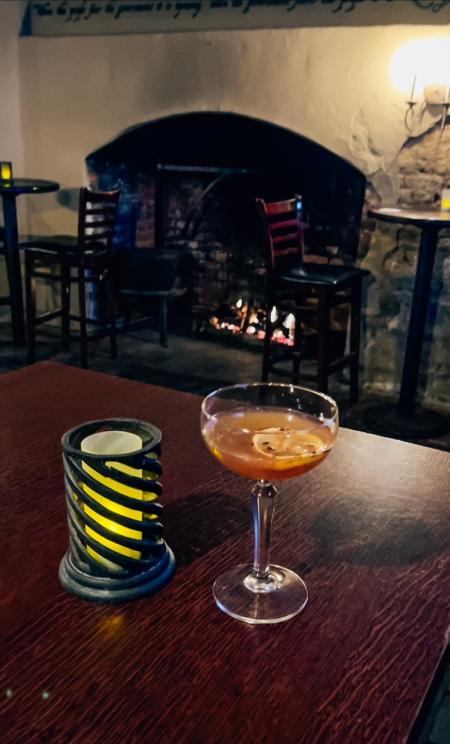 A drink on a table in front of a roaring fire