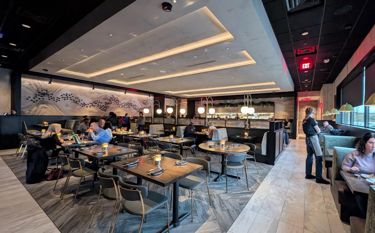 Interior of Cooper's Hawk restaurant with people seated at several tables in a modern, upscale room.