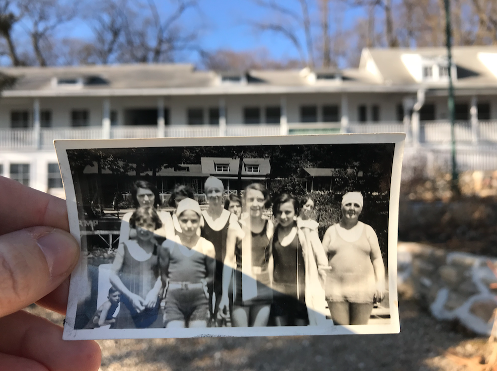 Person holding a vintage photo of Norman B. Barr Camp with the current camp in the background
