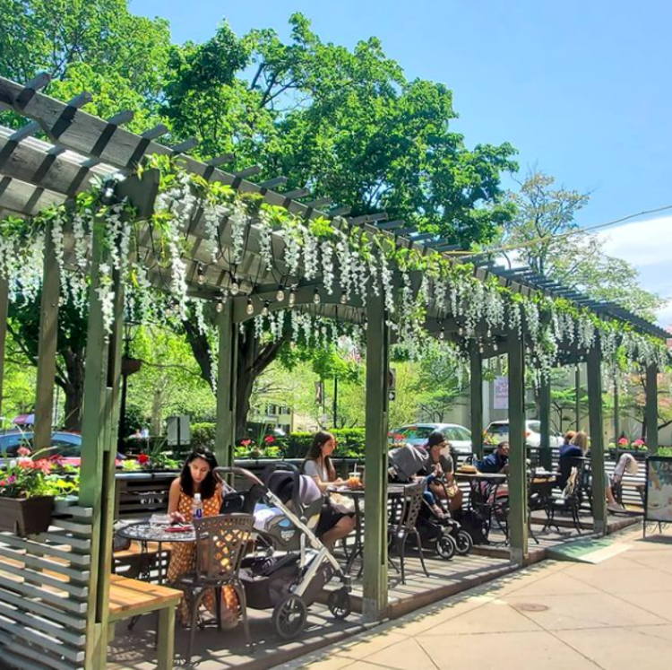 Outdoor tables with flowers draped over the roof