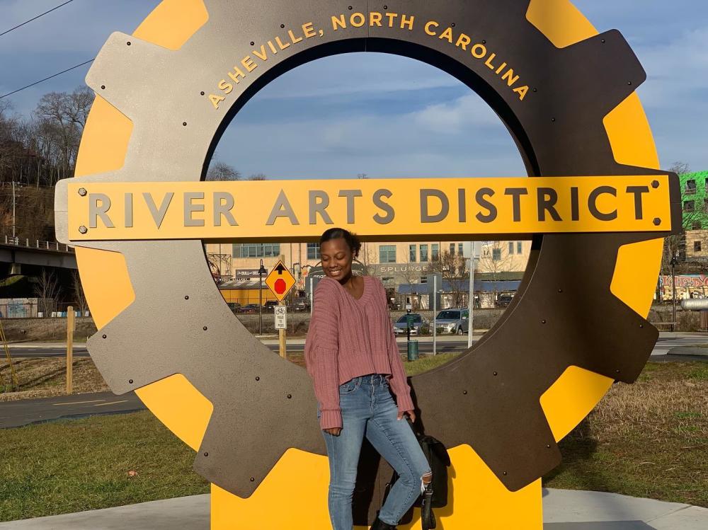 A woman poses with new signage in the River Arts District in Asheville, NC