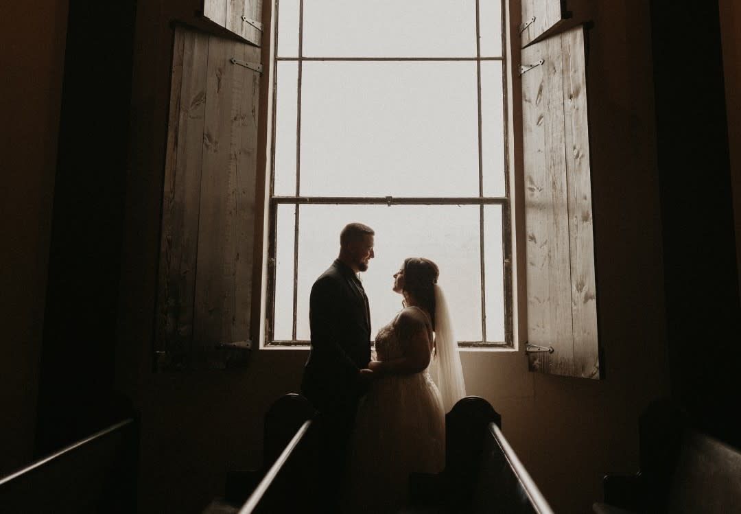 Bride and groom in front of large window