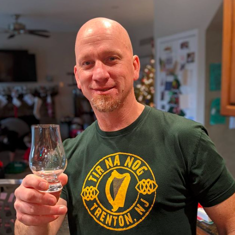 A man holding an empty whiskey glass at Tir na nOg in Trenton, NJ