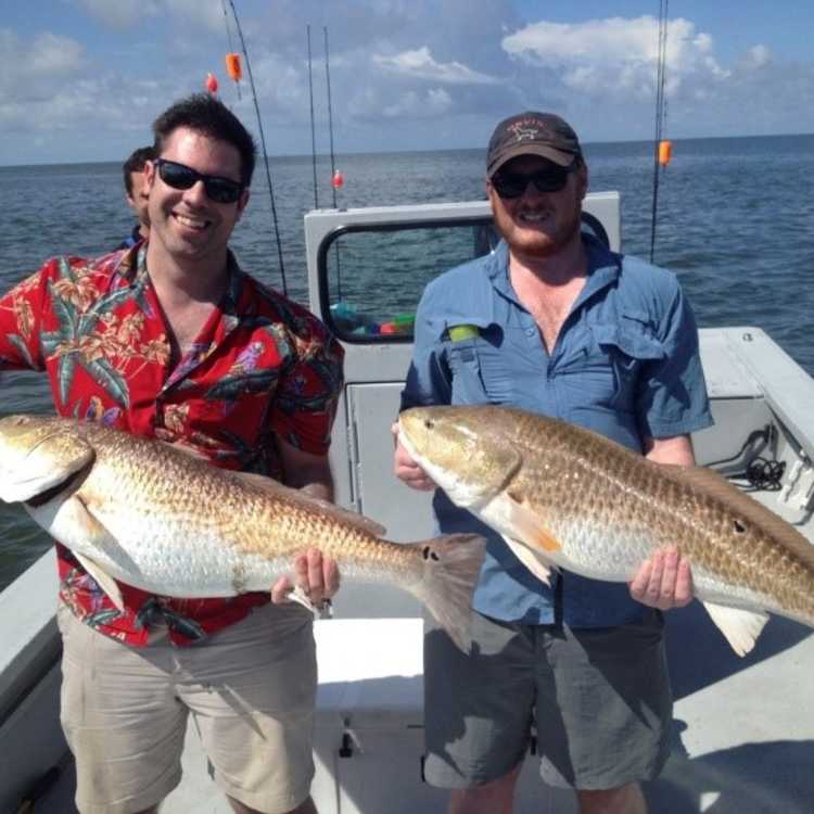 Two people pose with large fish they've caught