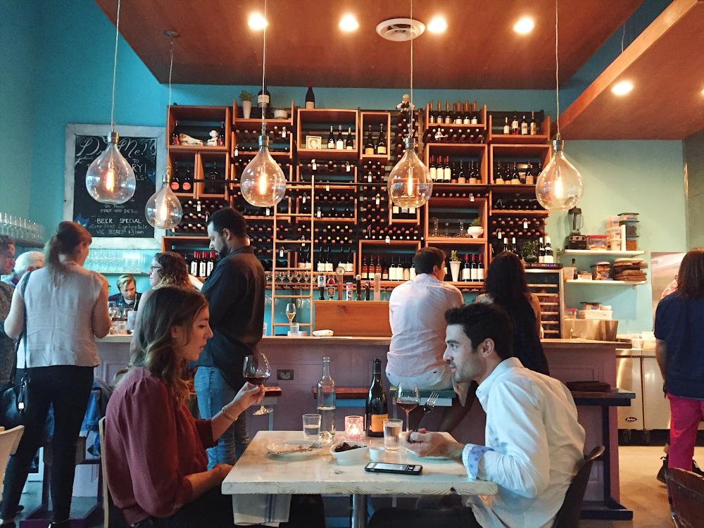 couple dining at aviary in front of bar and wine racks