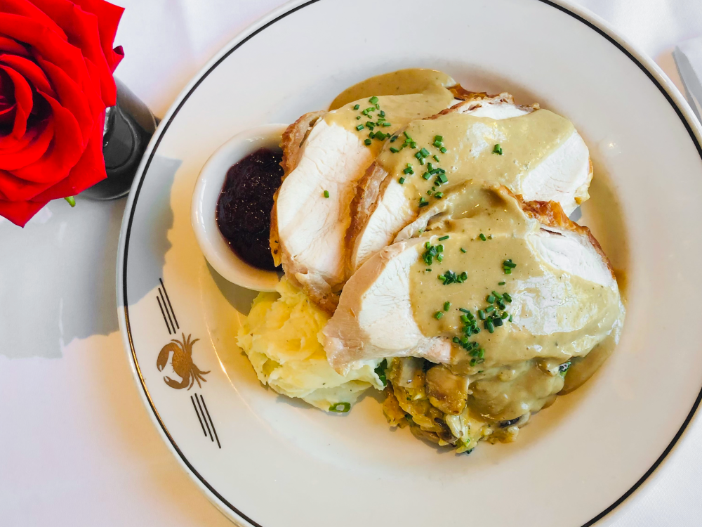 Plate gilded with golden Truluck's crab emblem, topped with a pile of mashed potatoes, turkey breast slices and brown gravy.