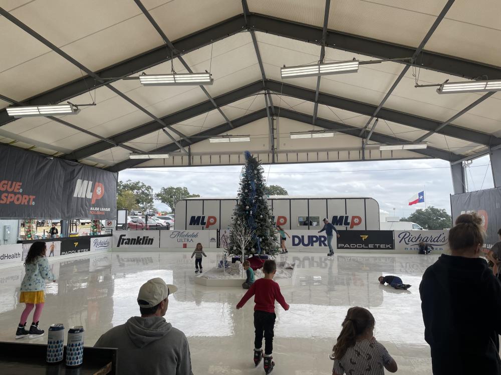 Children and adults skating at Dreamland's covered, synthetic ice skating rink.