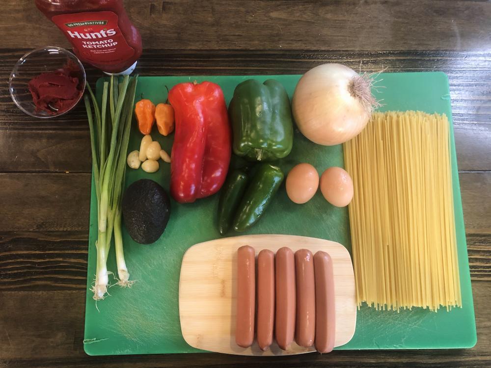Kreyol Korner Haitian Spaghetti Ingredients including bell peppers spaghetti yellow and green onion hotdogs and spices