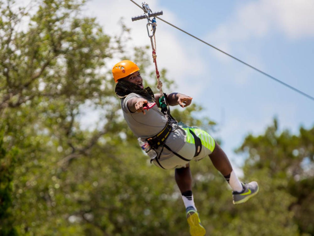 Man riding Lake Travis Zip Line points back to camera