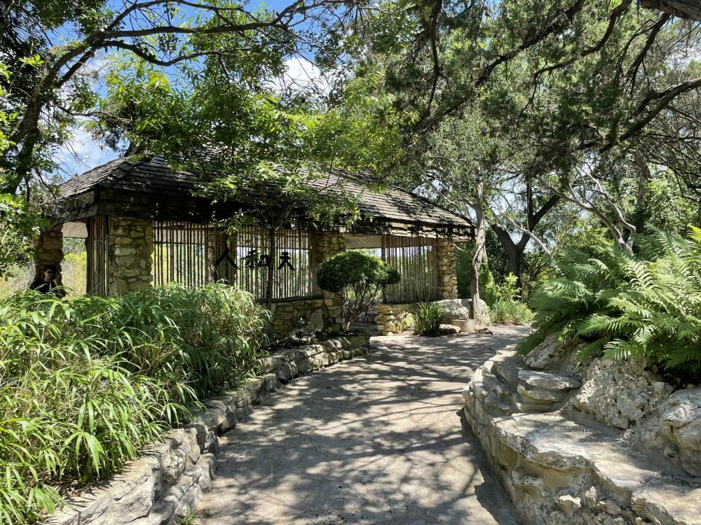 Shaded concrete pathway in the Taniguchi Japanese Garden at Zilker Botanical Garden.