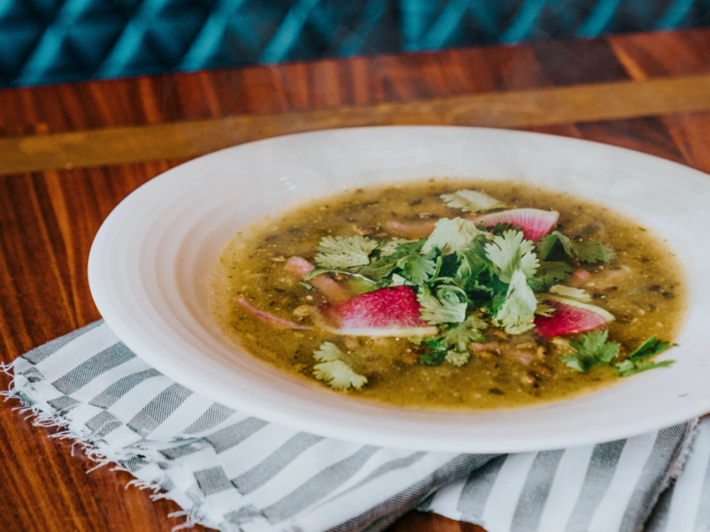 Bowl of Chicken Posole from Local Foods. The soup is topped with fresh cilantro and sliced radish