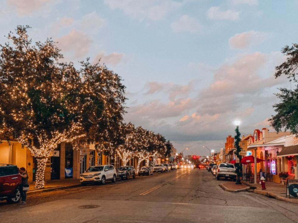 Downtown Bastrop street with trees on the sidewalk wrapped in lights