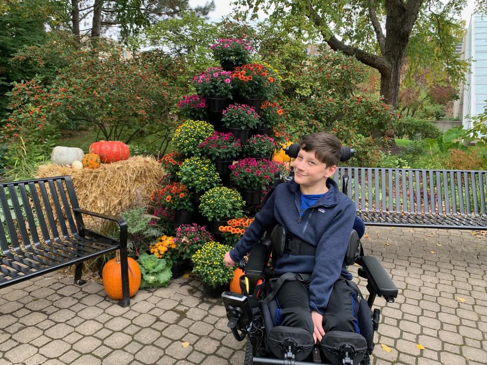 Donahue's son in front of fall pumpkins and floral arrangement.