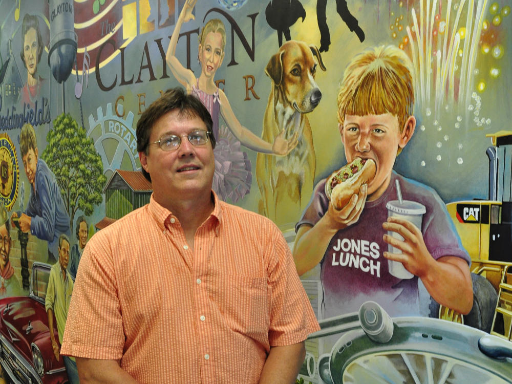 Jim Brown stands in front of the mural he painted in the Clayton Library