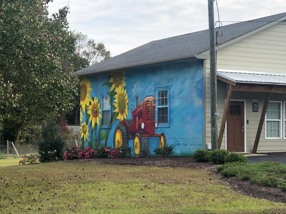 A tractor and sunflower mural on the side of a building in Clayton, NC.