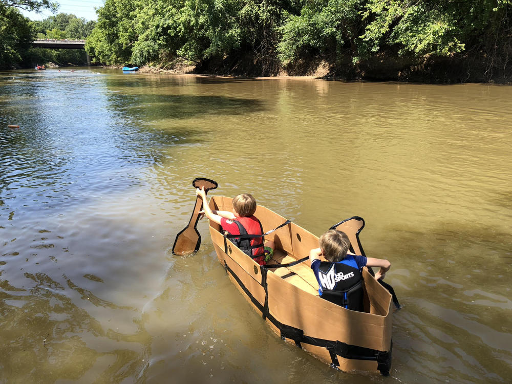 Two Kids Paddle a Cardboard Boat Along The Neuse River