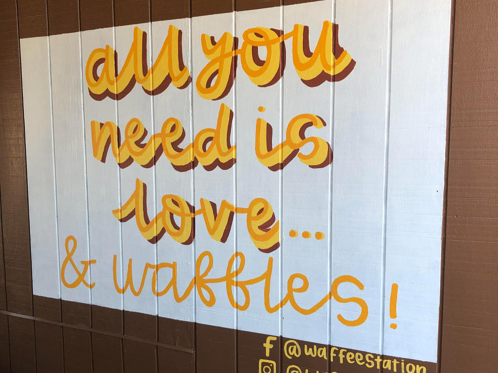 Mural at Waffee Station that says "all you need is love...& waffles!" in Micro, NC.