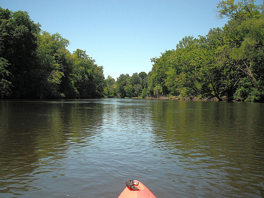 An orange kayak is centered in the middle of Morrow Lake, a lake in Kalamazoo County perfect for kayaking.