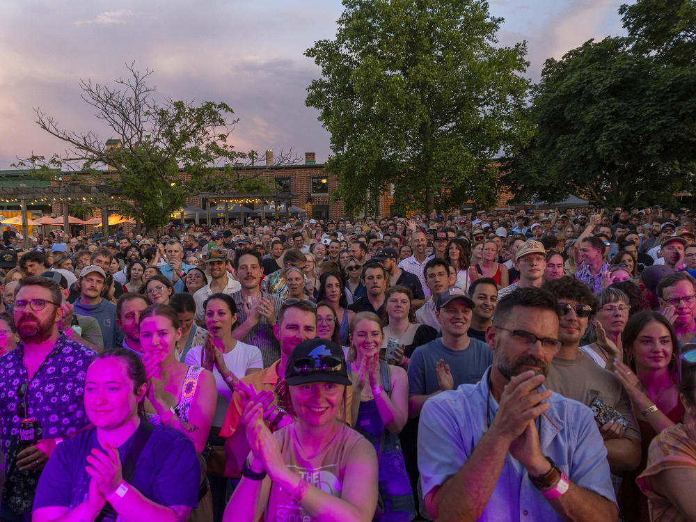 A large crowd of people in Bell's Beer Garden cheer a performing band on stage during Bell's Brewery and Eccentric Cafe's Summer Concert Series.