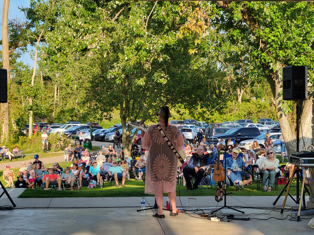 A woman performs on stage facing an audience at the Celery Flats during Friday at the Flats, a free summer concert series.