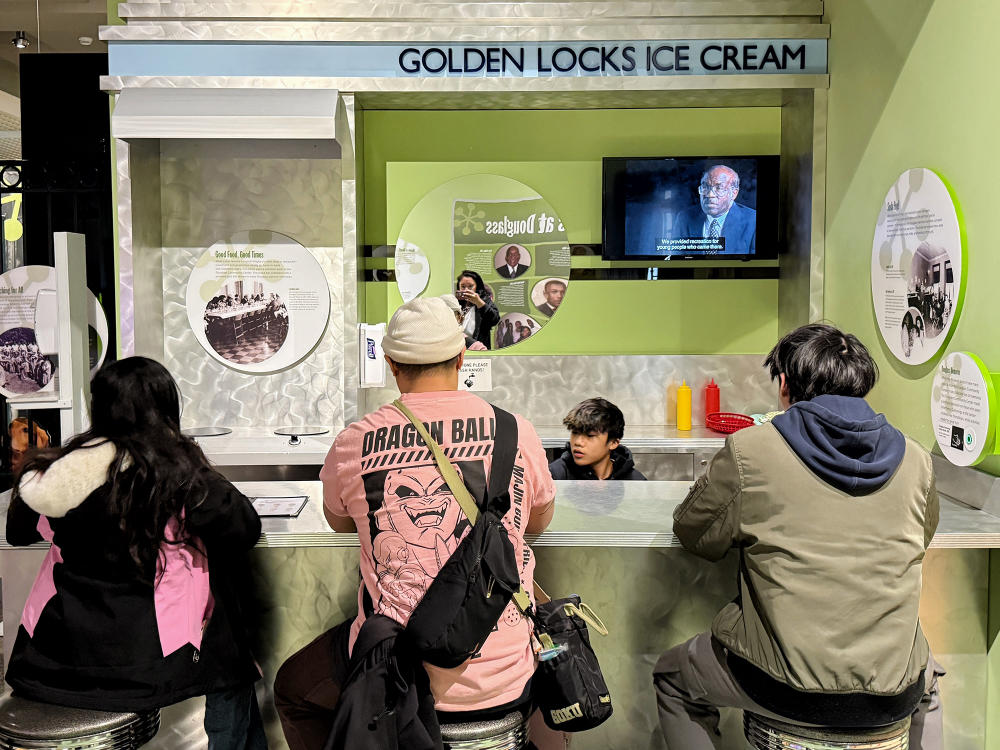Three individuals sit at the space for Golden Locks Ice Cream Display at the Kalamazoo Valley Museum in Downtown Kalamazoo.