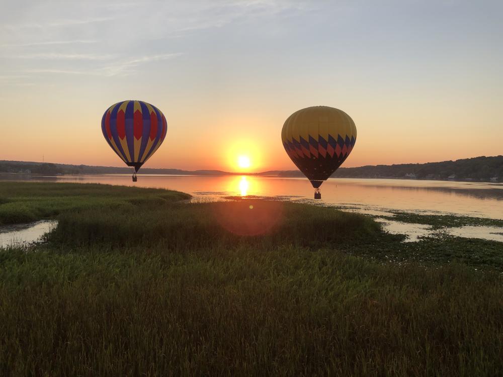 Two balloons flying over Lake Como at sunset.
