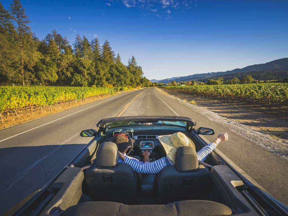 Visitors enjoy the sunshine and fresh air in their convertible on a drive through Napa Valley.