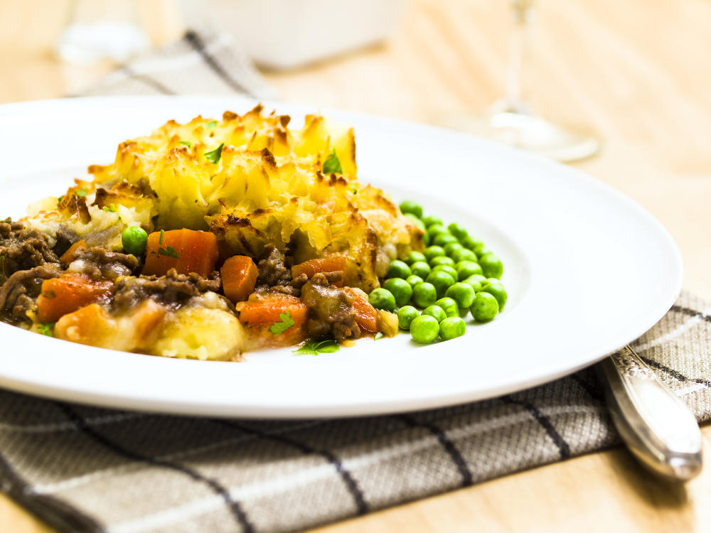 A plate of phepherd's pie with peas