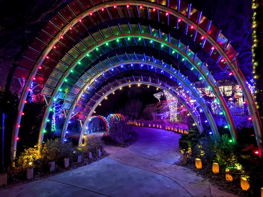 The arches of the Children's Garden Entrance are illuminated red, green, blue and yellow at Botanica Illuminations