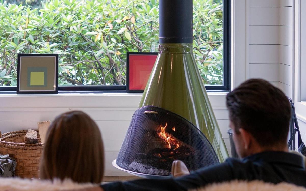 Two people sitting on a couch looking at a retro green fireplace and relaxing