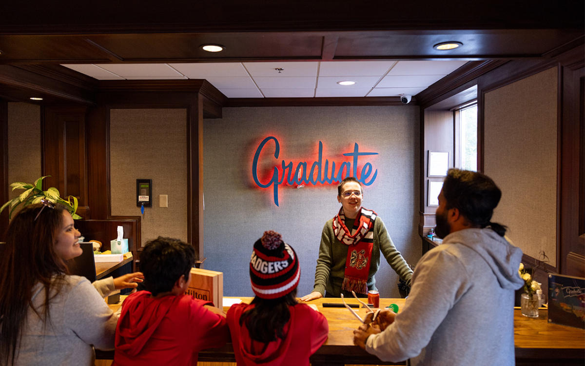 A family of sports fans visit The Graduate hotel front desk in Madison, WI