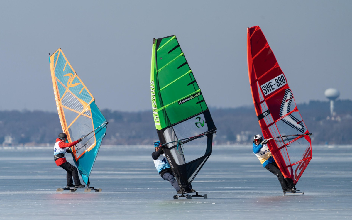 Three athletes competing in a snow sailing sports competition in Madison, WI