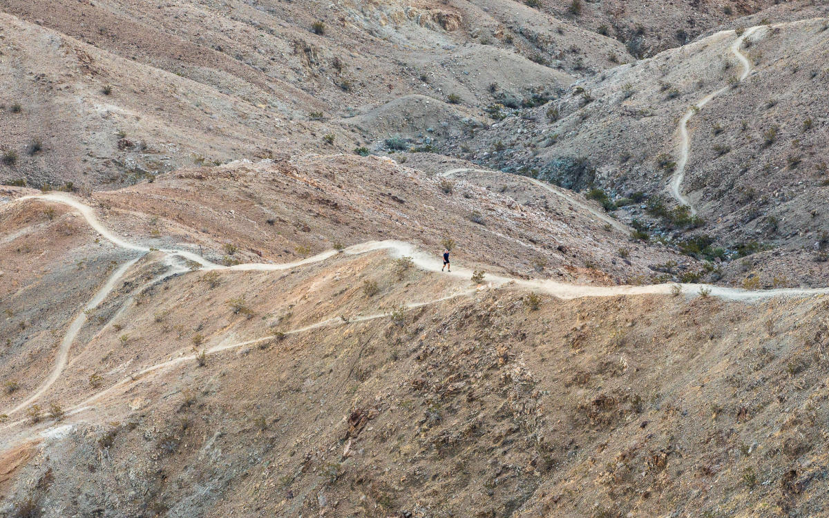 A man hikes on the Bump and Grind Trail in Palm Springs, social trails visible off the main trail.