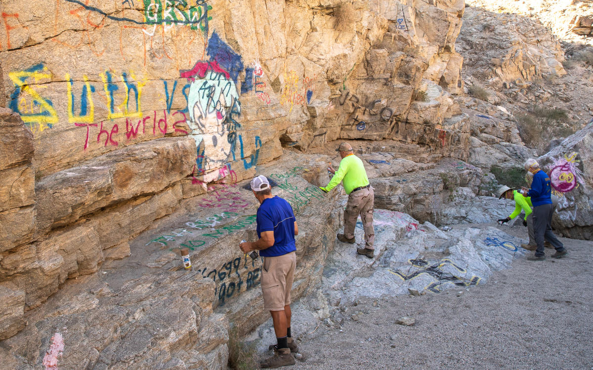 Volunteers from Friends of the Desert Mountains remove graffiti near a trail in La Quinta.