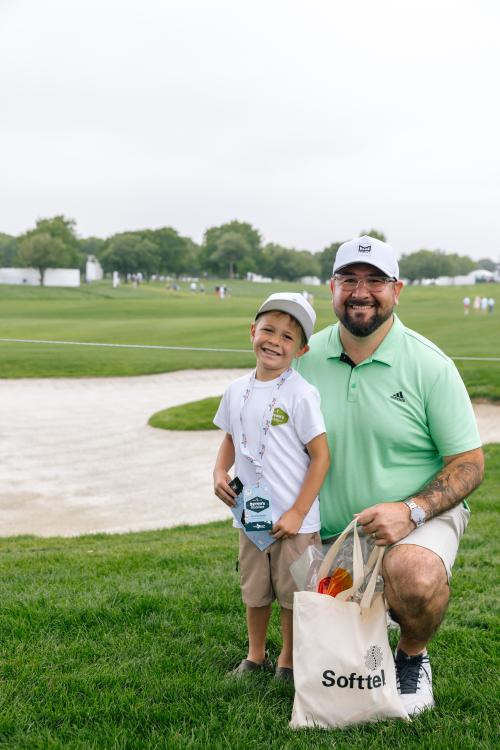 Father and son standing on the green at a golf course smiling at the camera having fun