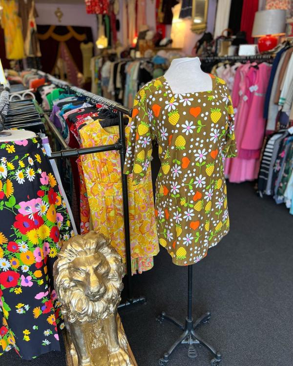 A mod dress from Avengers Vintage sits on a mannequin in front of racks of clothes